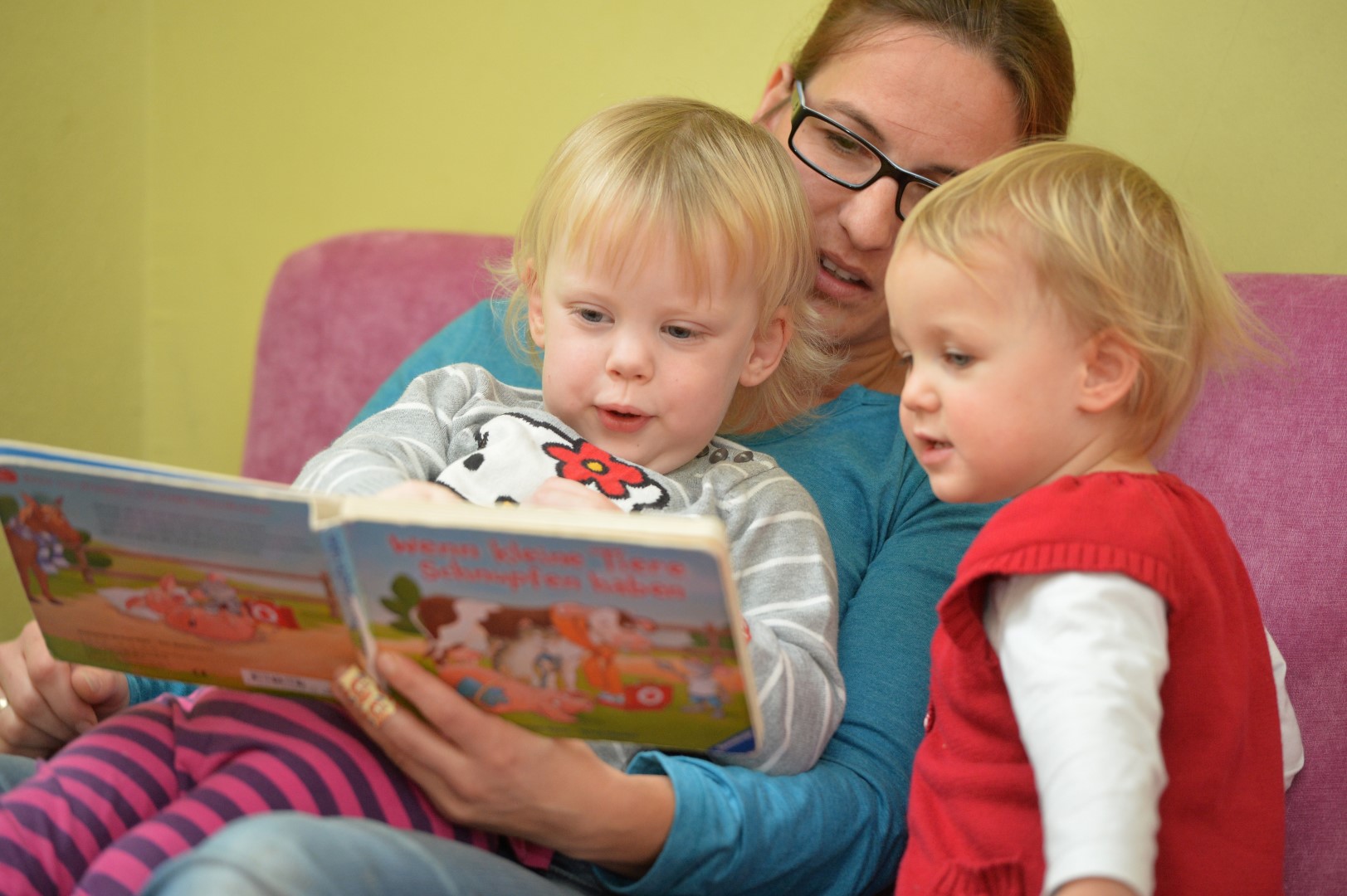 Erzieherin in der Flohkiste Lauterbach mit Kinderkrippen Kindern beim vorlesen. 